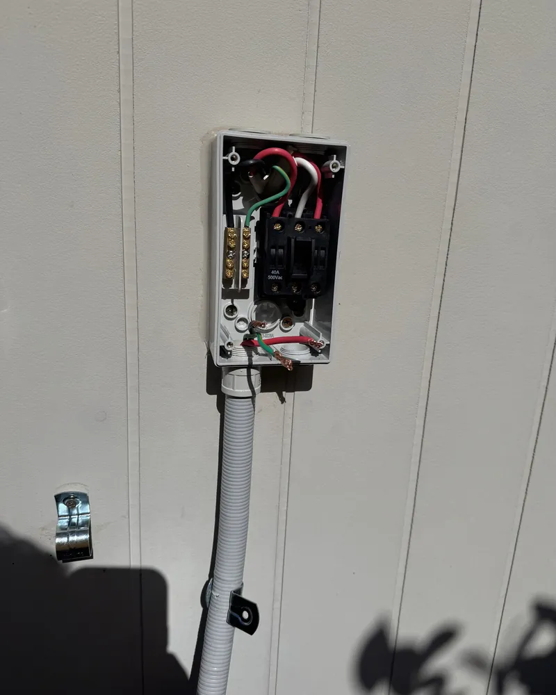 External isolator enclosure with conduit run down a rendered wall